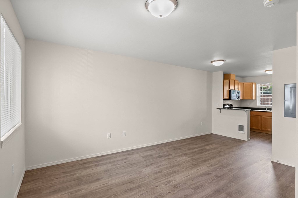 an empty living room and kitchen with wood flooring and white walls at Trillium Apartments, Oregon