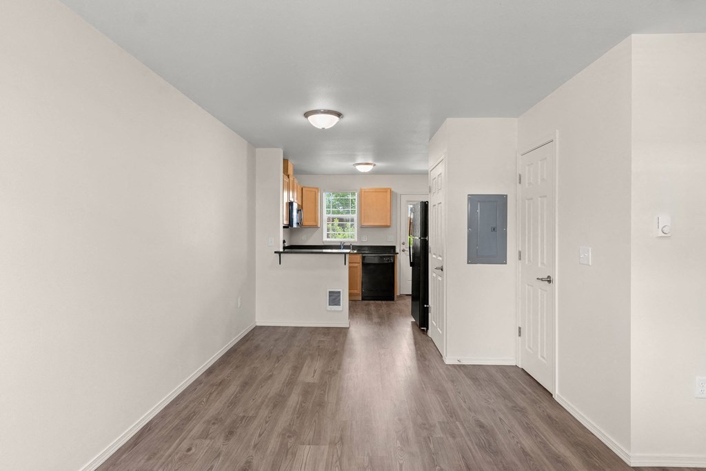 a renovated living room and kitchen with white walls and wood floors at Trillium Apartments, Oregon