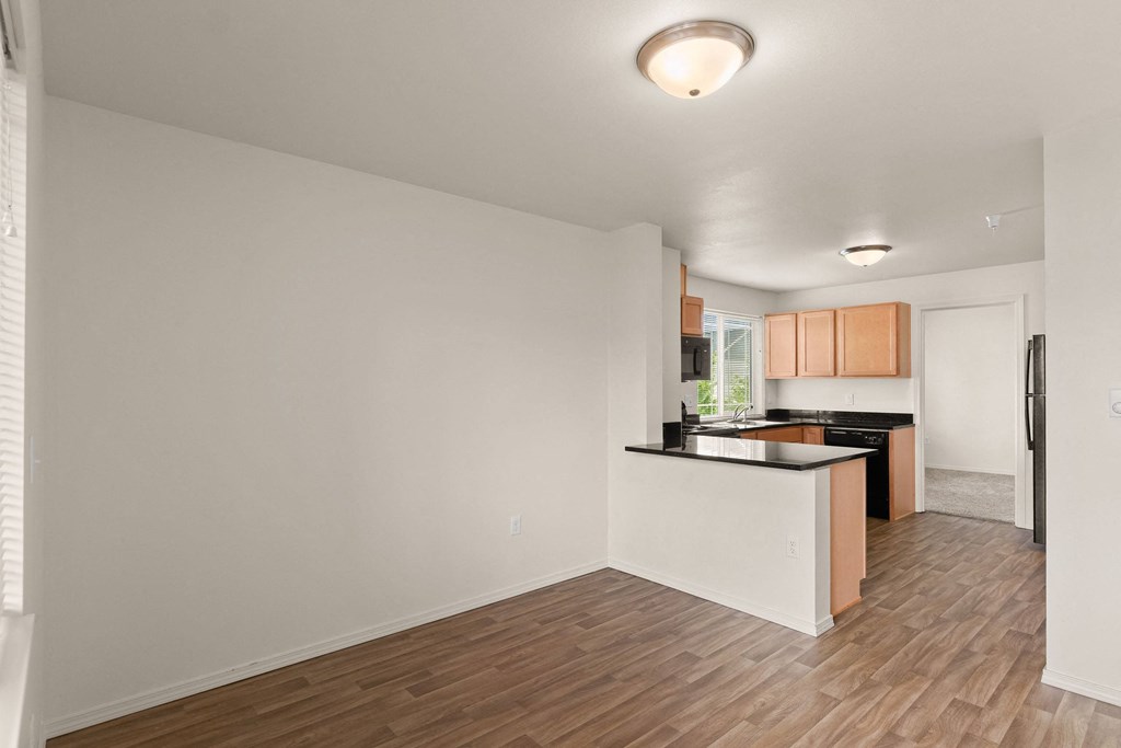 an empty living room and kitchen with wood flooring at Trillium Apartments, Springfield