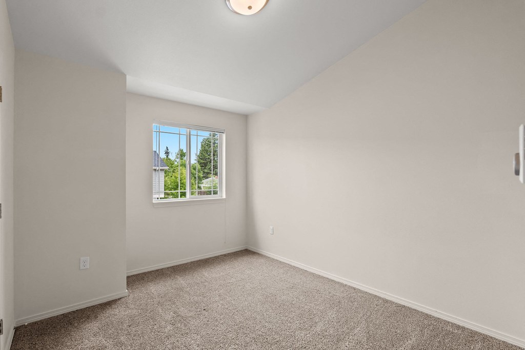 an empty bedroom with carpet and a window at Trillium Apartments, Springfield, Oregon