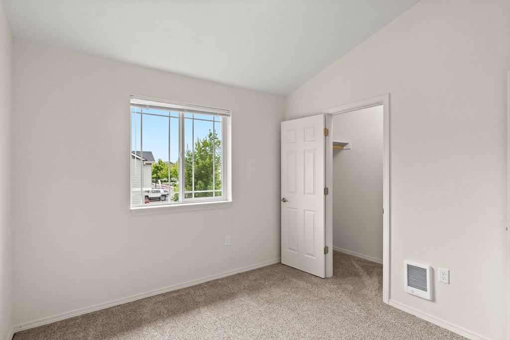 an empty bedroom with a window and a closet at Trillium Apartments, Oregon