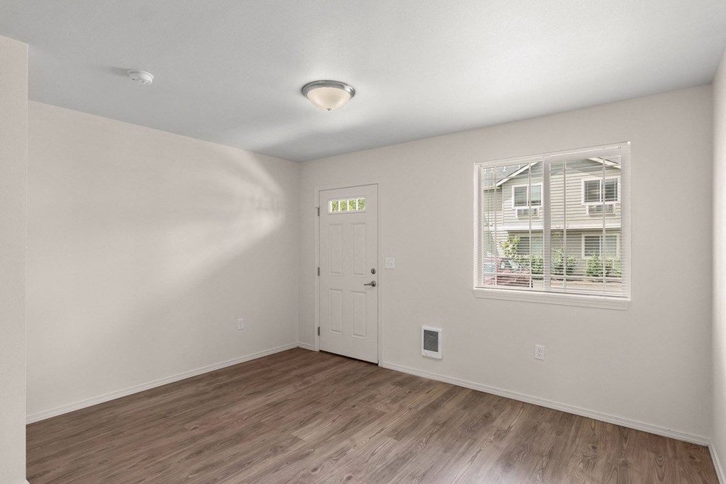 an empty living room with a door and a window at Trillium Apartments, Springfield, Oregon