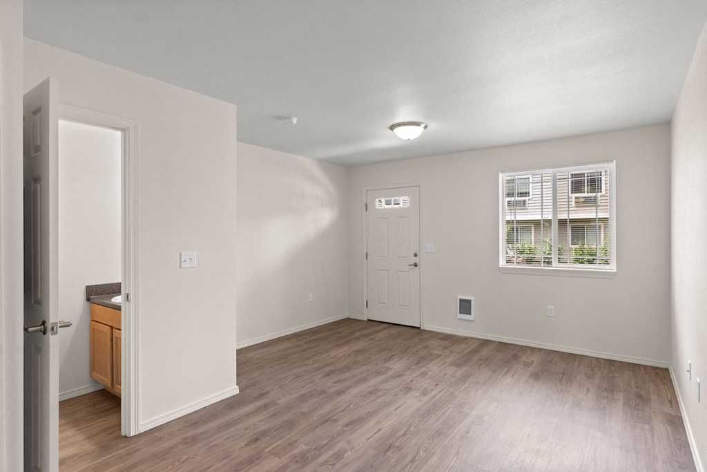 the living room of an apartment with wood flooring and a door to the kitchen at Trillium Apartments, Springfield, OR