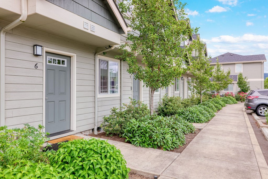 a sidewalk in front of a gray house with a blue door at Trillium Apartments, Springfield, OR, 97477