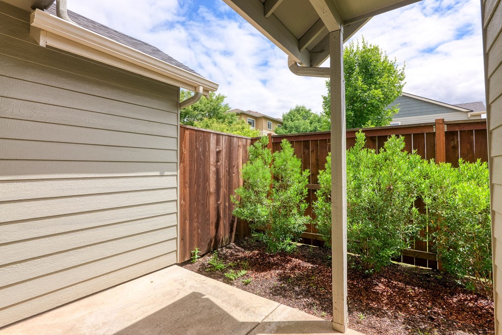 a side view of a house with a yard and a fence at Trillium Apartments, Springfield, OR, 97477