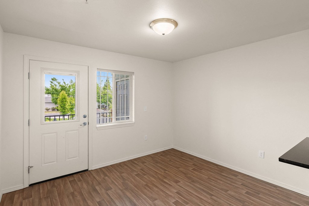 an empty living room with white walls and a door to a balcony at Trillium Apartments, Springfield, Oregon