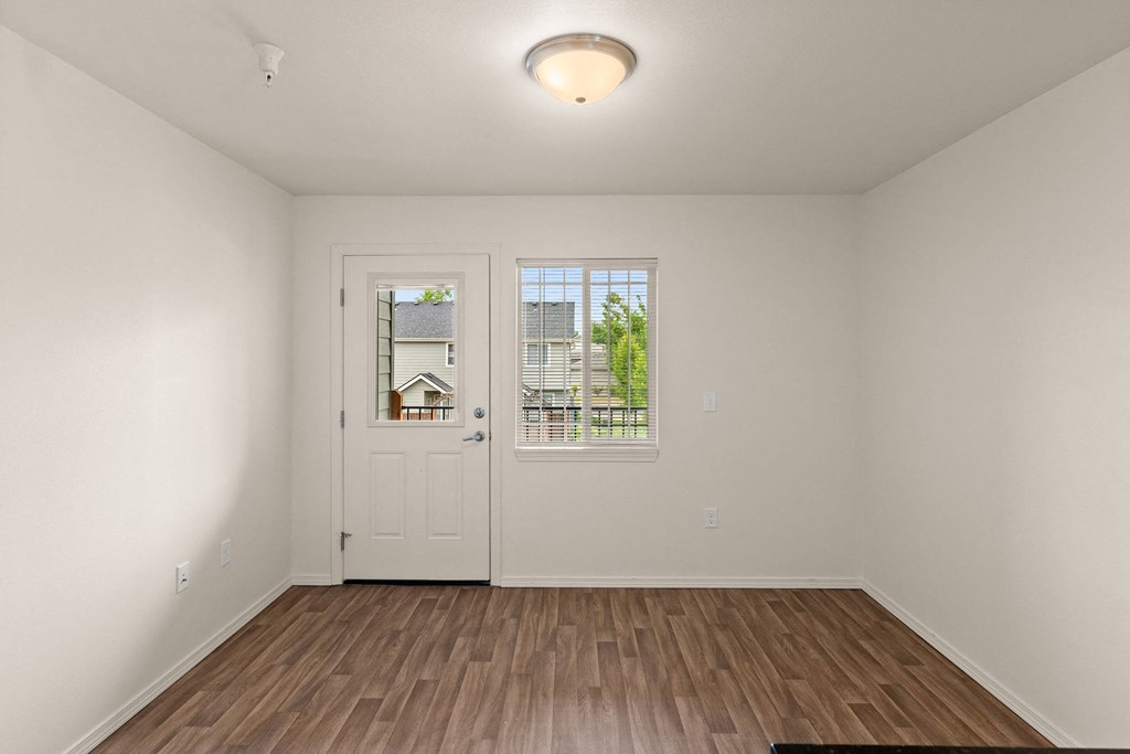 a living room with white walls and a door to a balcony at Trillium Apartments, Springfield, Oregon