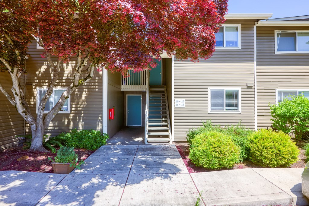 a walkway in front of a grey apartment building with a blue door at Chalet, Springfield, Oregon