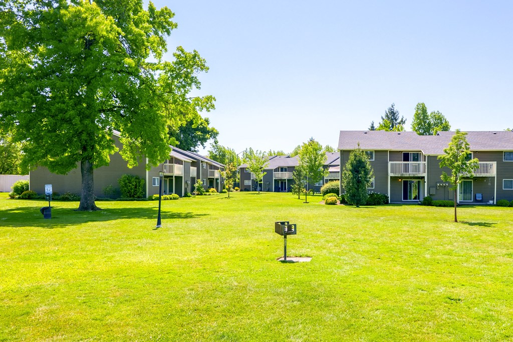 a grassy area with several apartment buildings in the background at Chalet, Springfield, OR