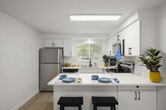 a kitchen with white cabinets and a white island with two black stools in front of it