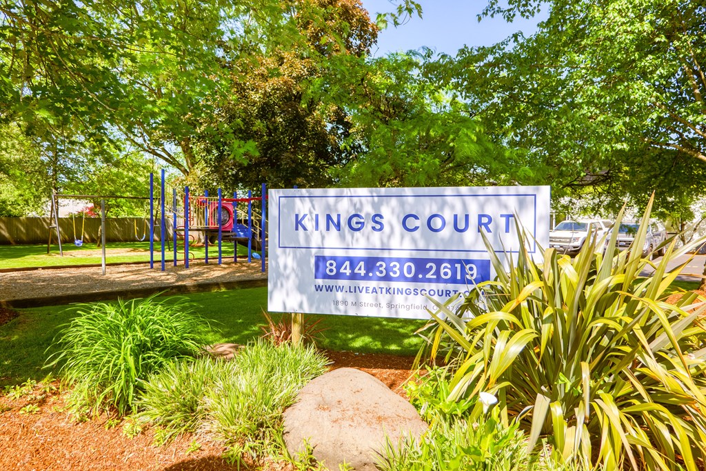 a sign that says kings court with a playground in the background