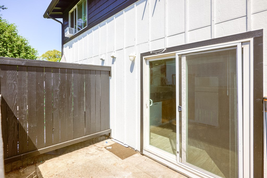 a patio with a sliding glass door and a wood fence