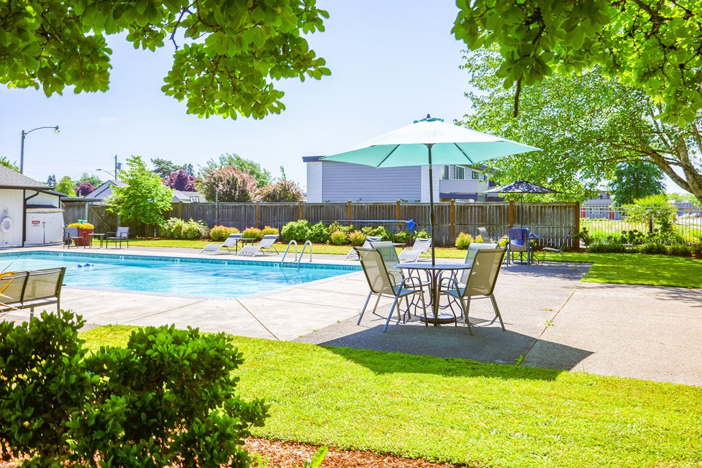 a patio with a table and chairs and a pool in the background