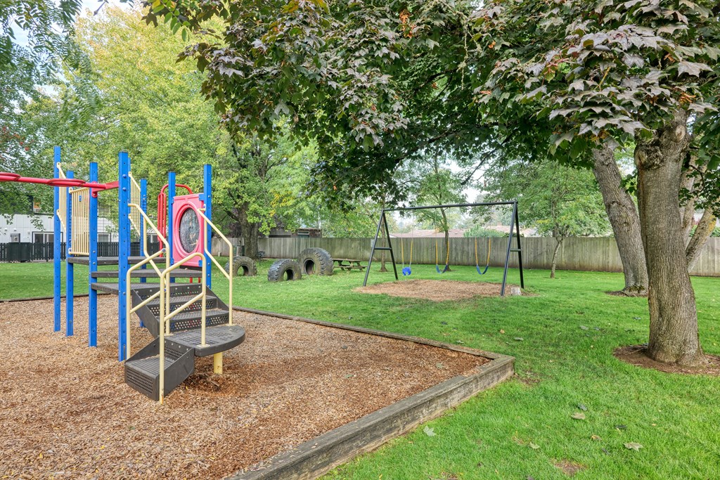 a playground with a swing set and a tree