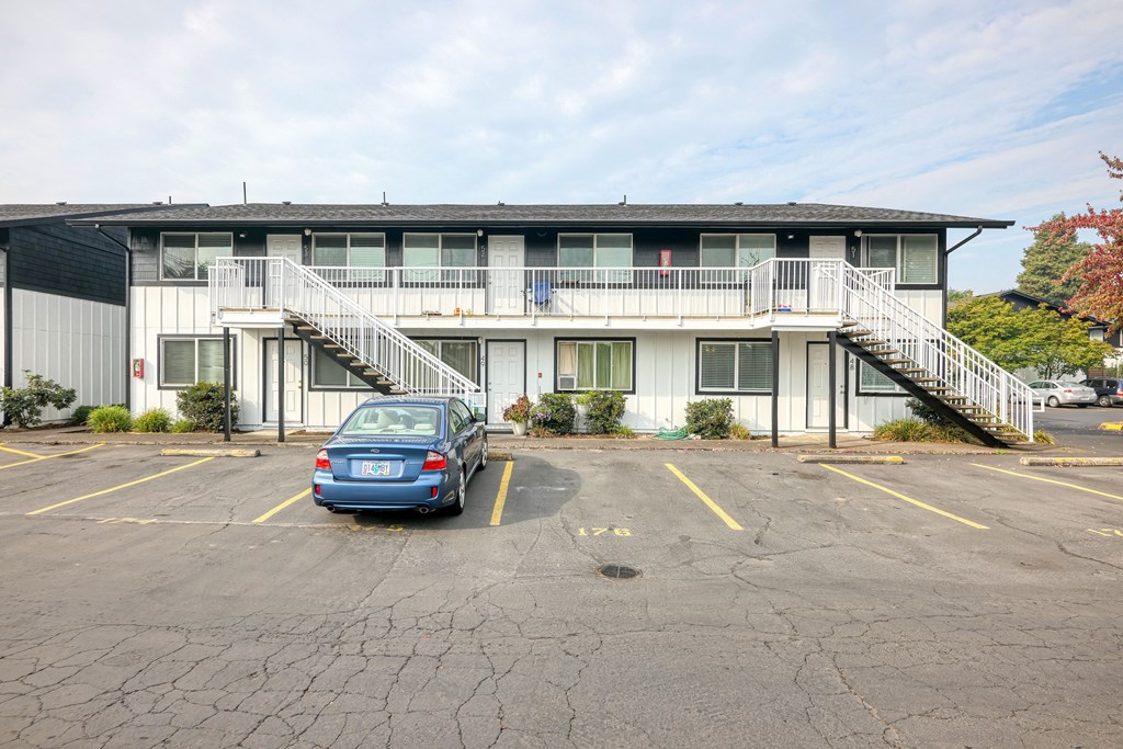 an empty parking lot in front of an apartment building with a car parked in front