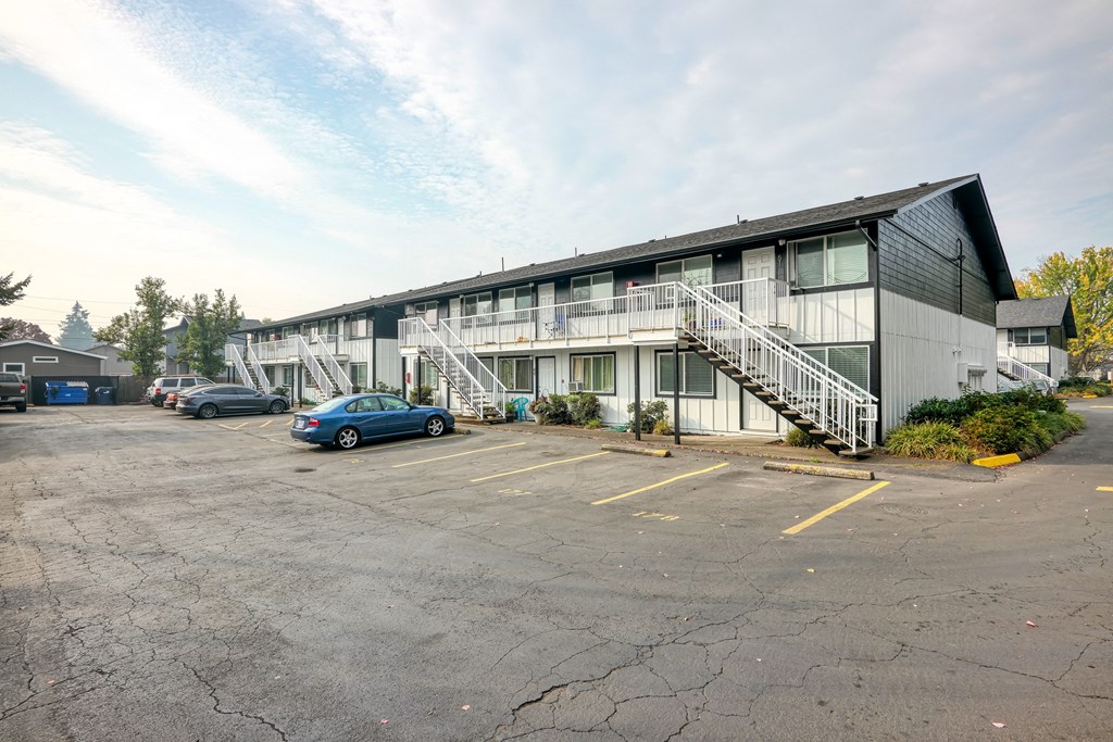the exterior of a motel with cars parked in front of it
