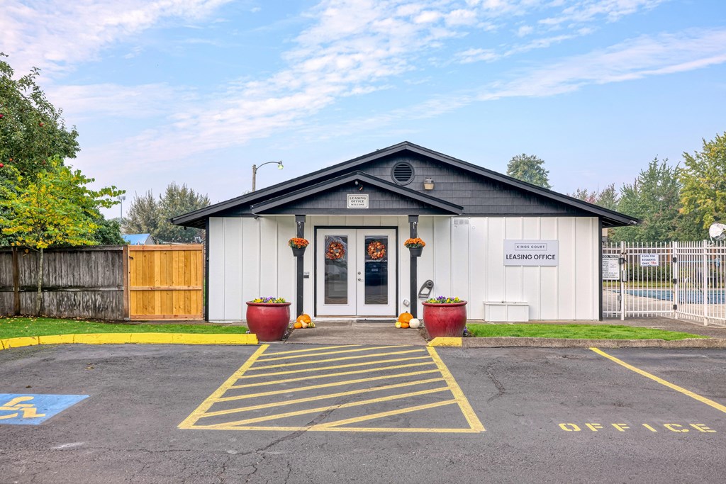 the front of a building with a driveway and a parking lot