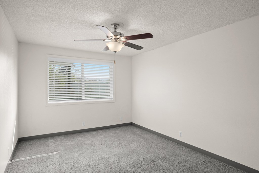 an empty room with a ceiling fan and a window