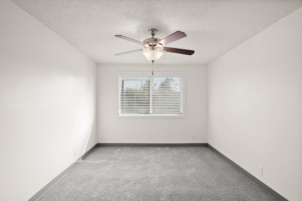 an empty room with a ceiling fan and a window