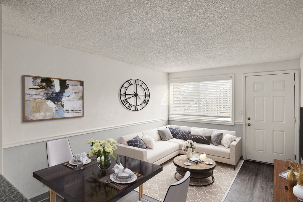 a living room with a couch table and chairs and a clock on the wall