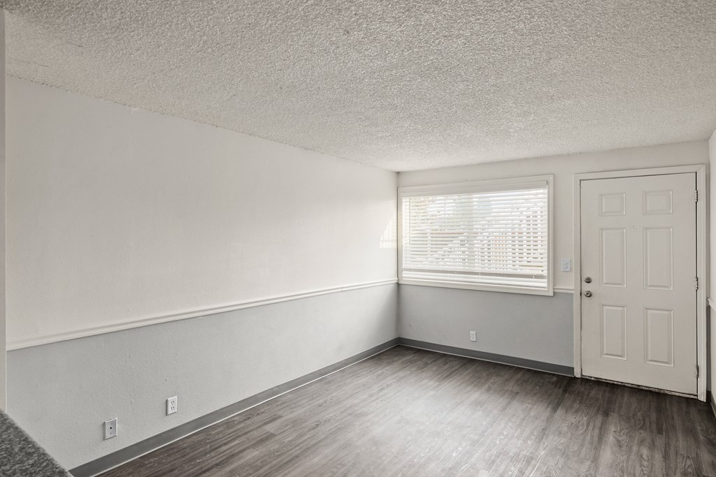 the living room of an apartment with white walls and a window