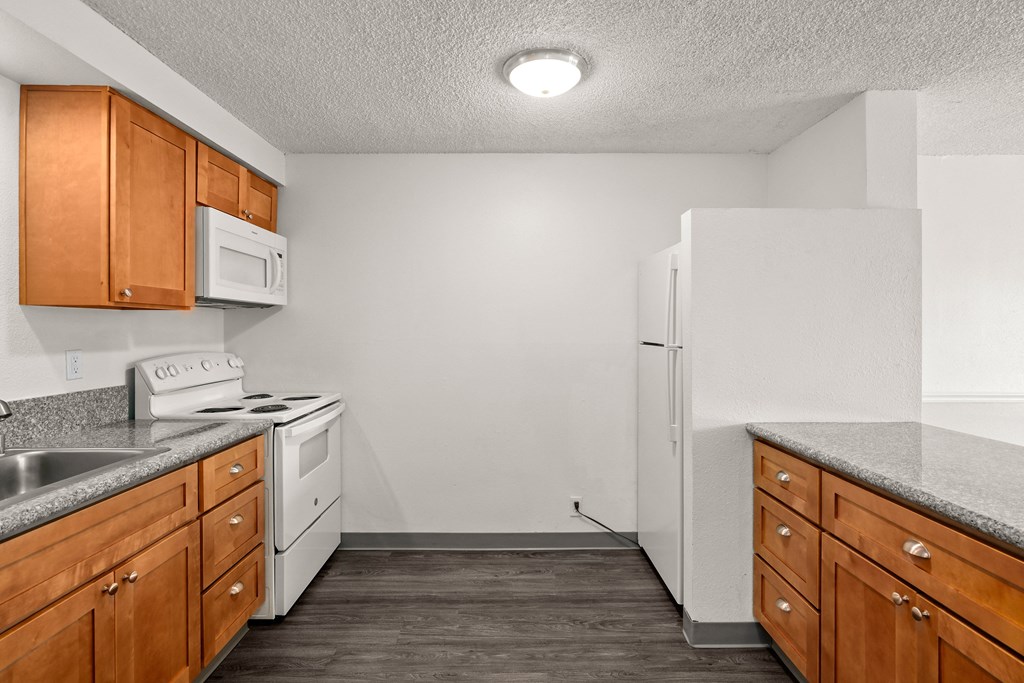 a kitchen with wood cabinets and white appliances and a refrigerator