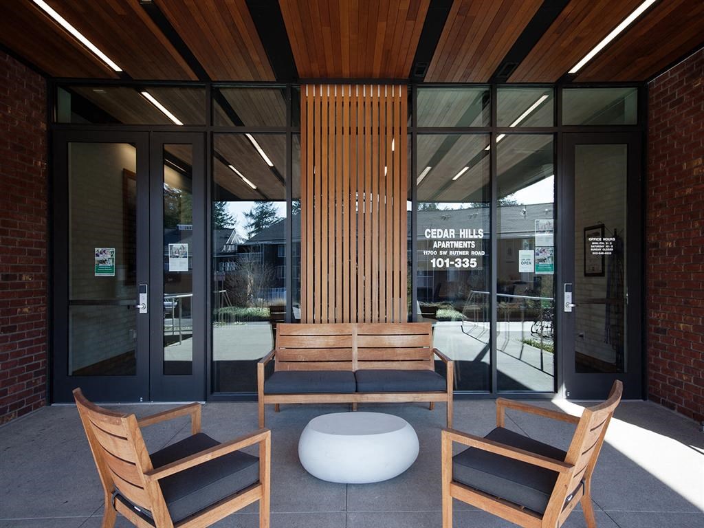 a seating area outside of a building with benches and glass doors