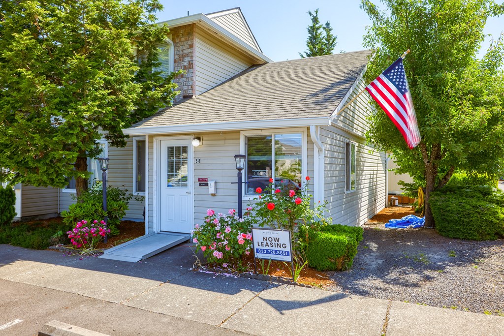 a small white house with an american flag in front of it