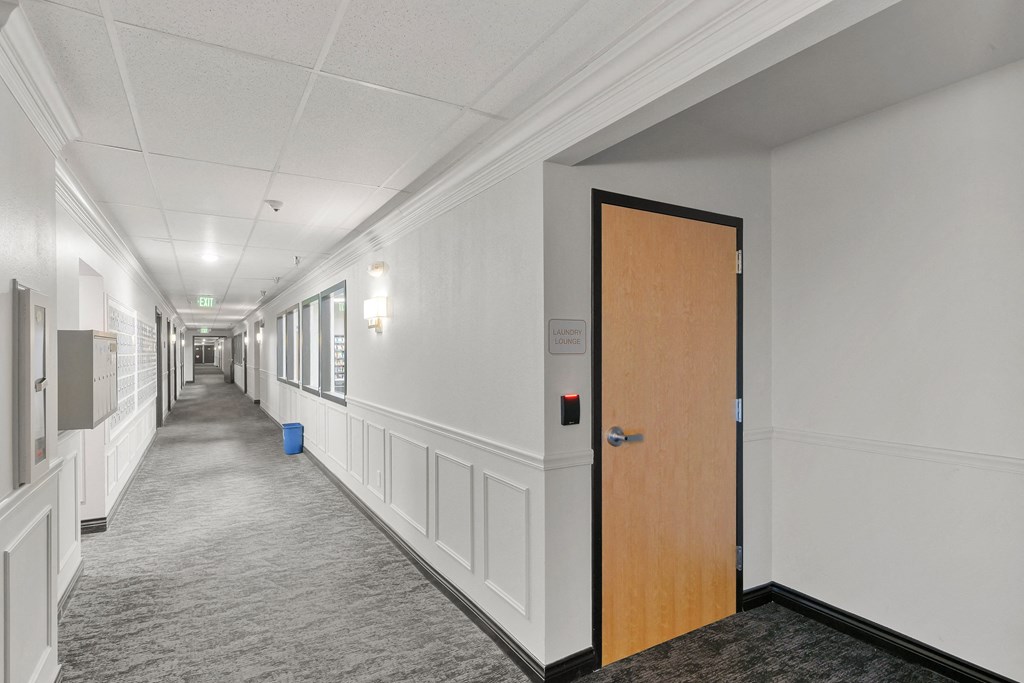 a hallway with white walls and a wooden door
