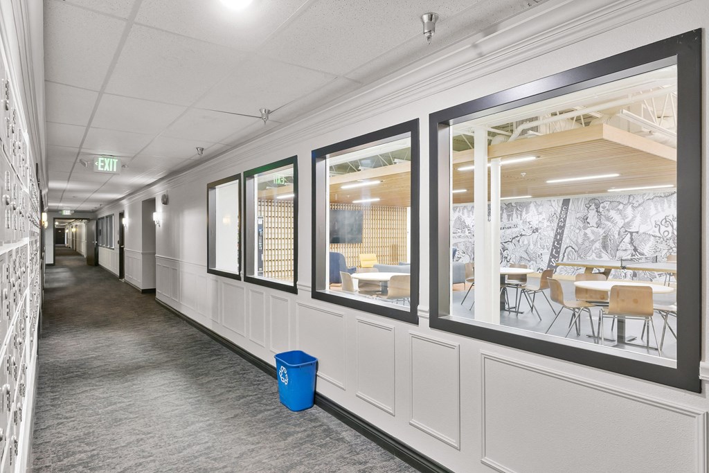 a hallway with windows and tables and chairs in a building
