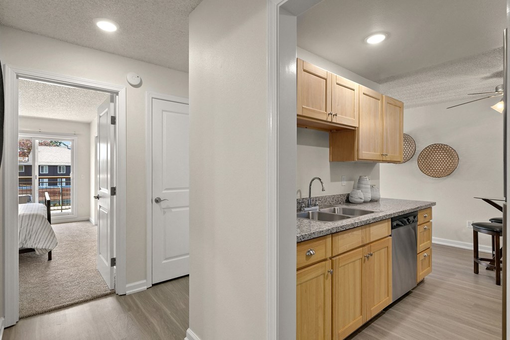 a kitchen with wood cabinets and a sink and a doorway to a bedroom