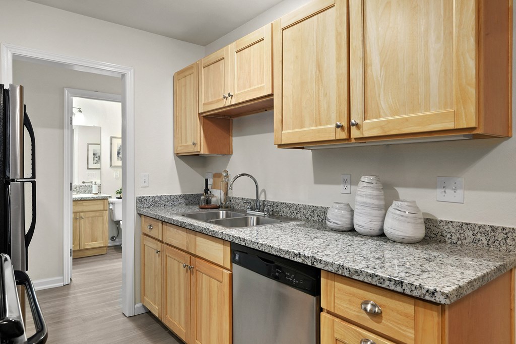 an empty kitchen with wooden cabinets and granite counter top