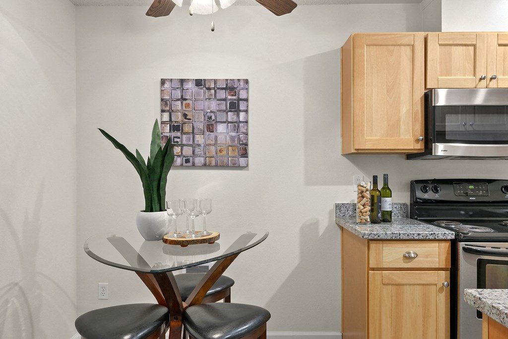 an apartment kitchen with a table and stools and a plant