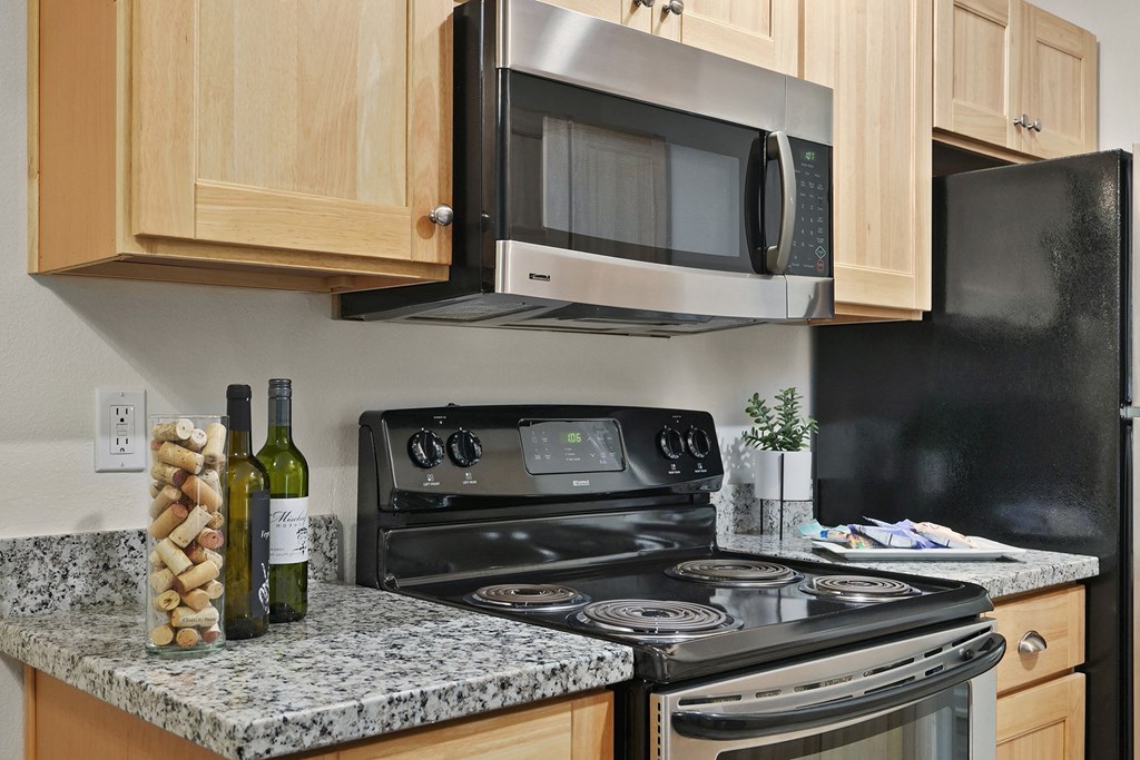 a kitchen with a stove and microwave and a counter with a bottle of wine