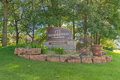 a stone retaining wall with a sign in front of trees