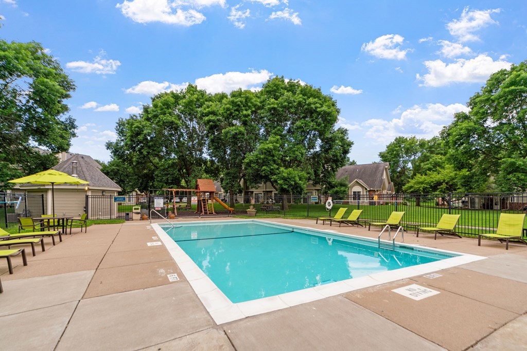 A large outdoor swimming pool surrounded by trees and lounge chairs.