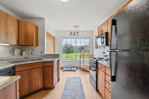A kitchen with wooden cabinets and a black refrigerator.