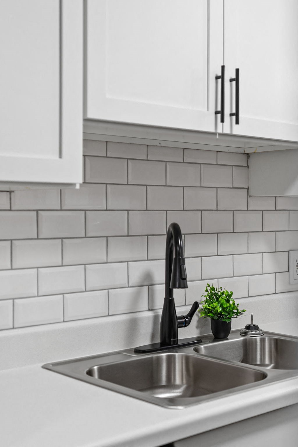 a white kitchen with a sink and white tiles