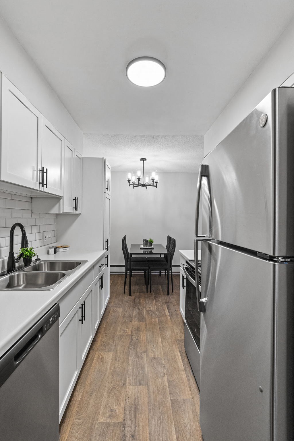 a kitchen with white cabinets and stainless steel appliances and a dining room table