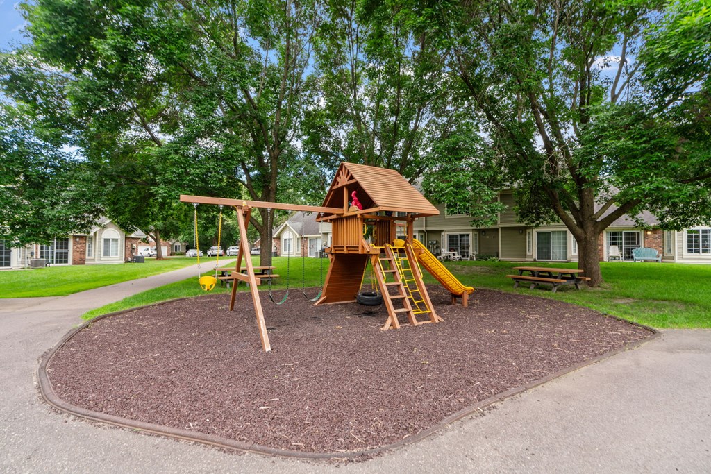 A playground with a wooden swing set and a yellow slide.