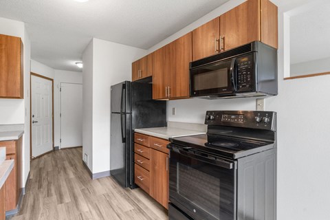 A kitchen with black appliances and wooden cabinets.