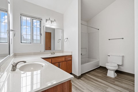 A white bathroom with a sink, mirror, toilet, and bathtub.