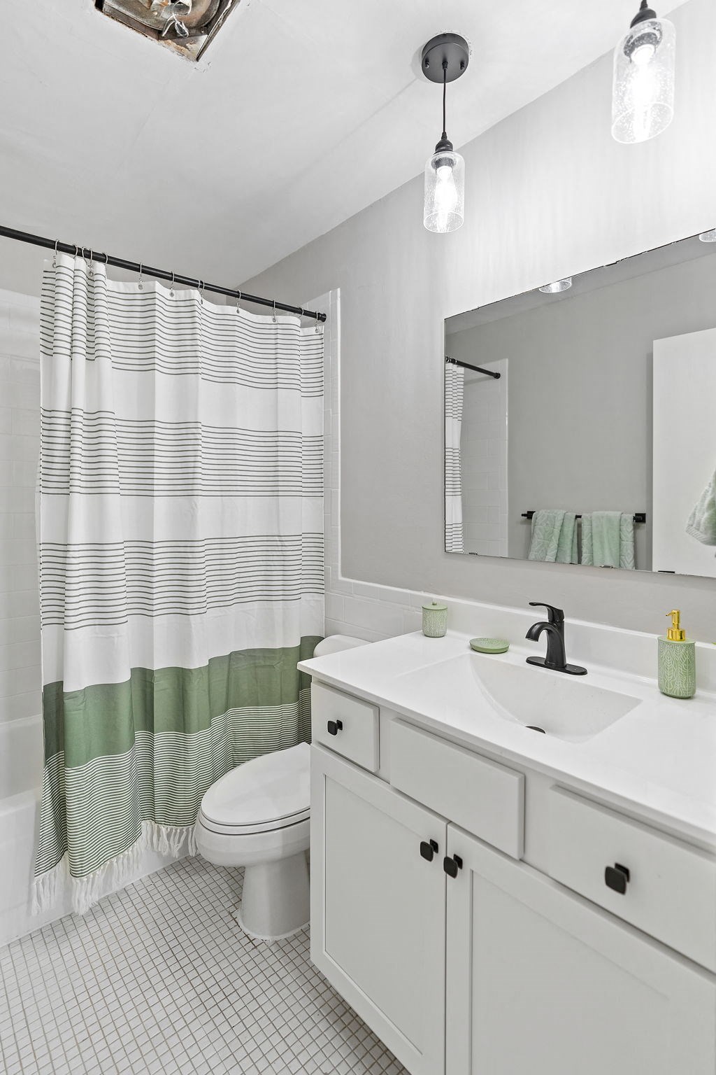 a white bathroom with a green and white striped shower curtain