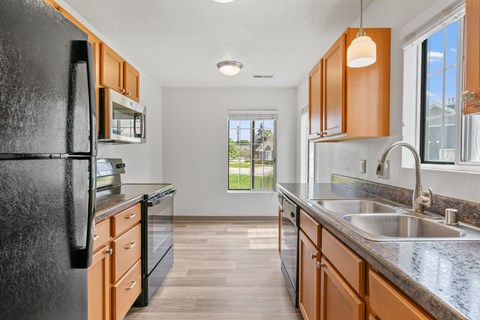 A kitchen with a black refrigerator and wooden cabinets.