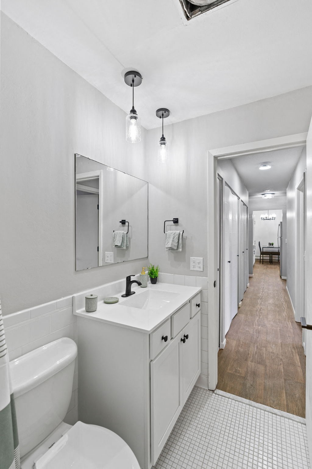 a long white bathroom with a toilet sink and mirror