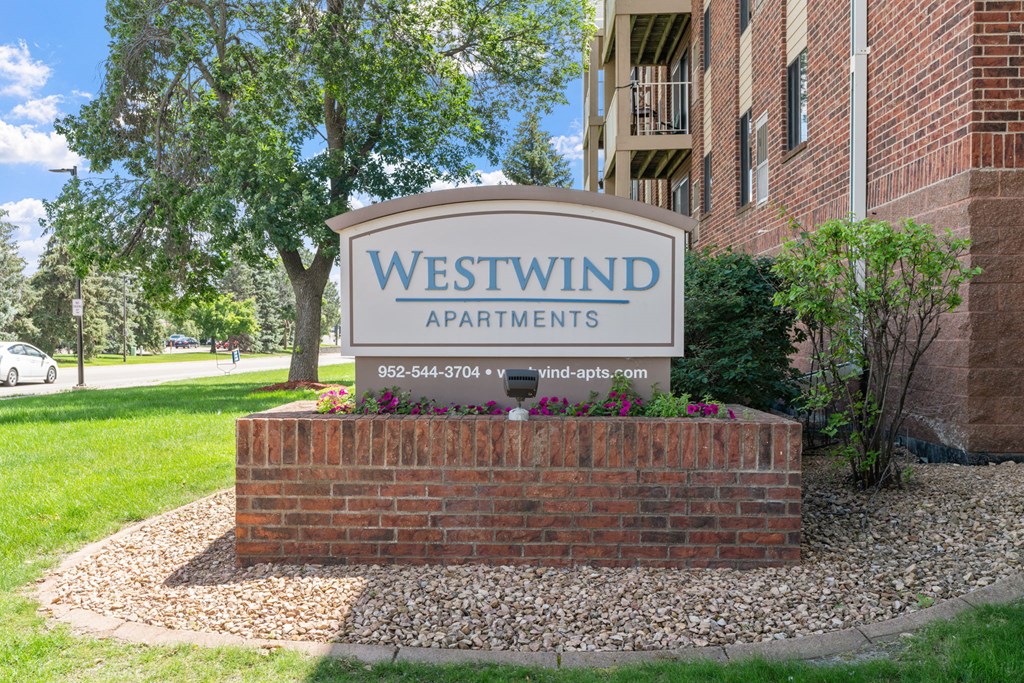 a sign for westwind apartments in front of a brick building