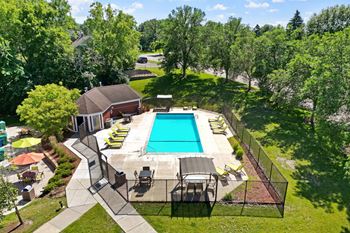 A pool surrounded by trees and a house.