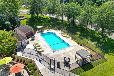 a backyard with a swimming pool and patio with chairs and umbrellas