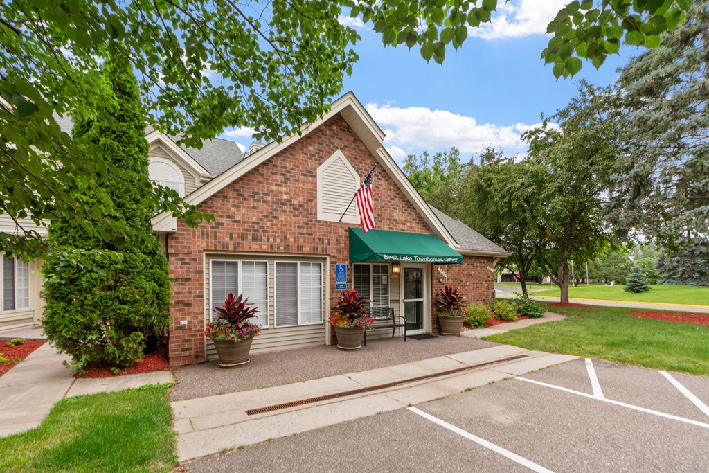 A small brick building with a green awning and an American flag on the front.