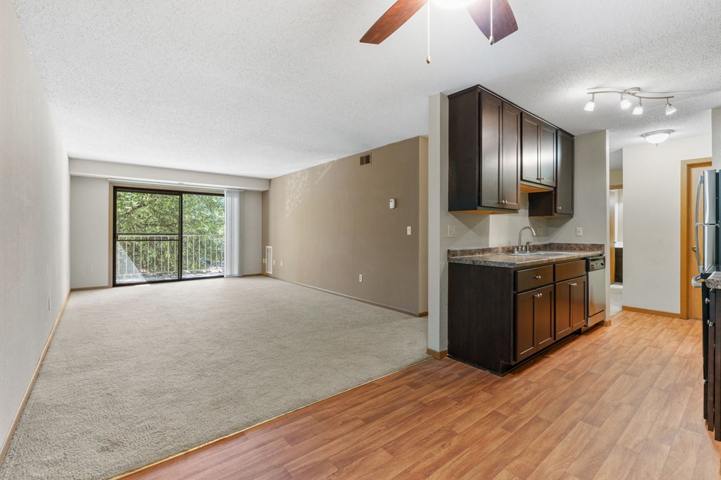 an empty living room and kitchen with wood flooring and a sliding glass door